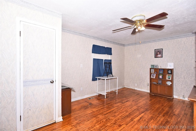 spare room featuring a ceiling fan, wood finished floors, crown molding, a textured ceiling, and baseboards