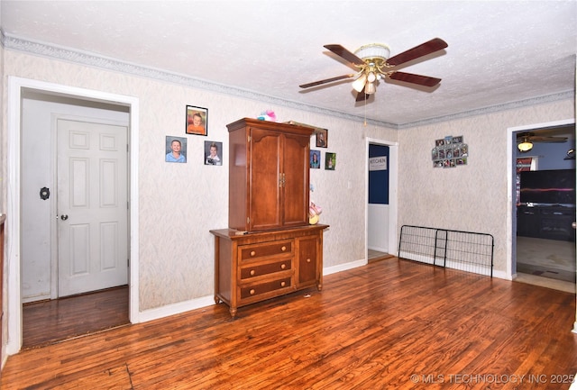 spare room featuring a ceiling fan, wood finished floors, crown molding, baseboards, and a textured ceiling