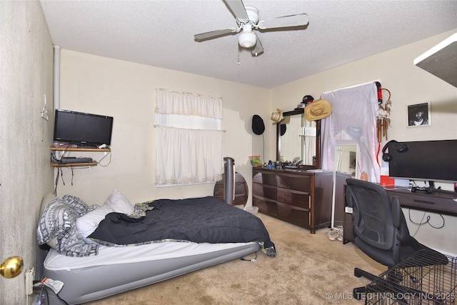 carpeted bedroom with an office area, a textured ceiling, and a ceiling fan