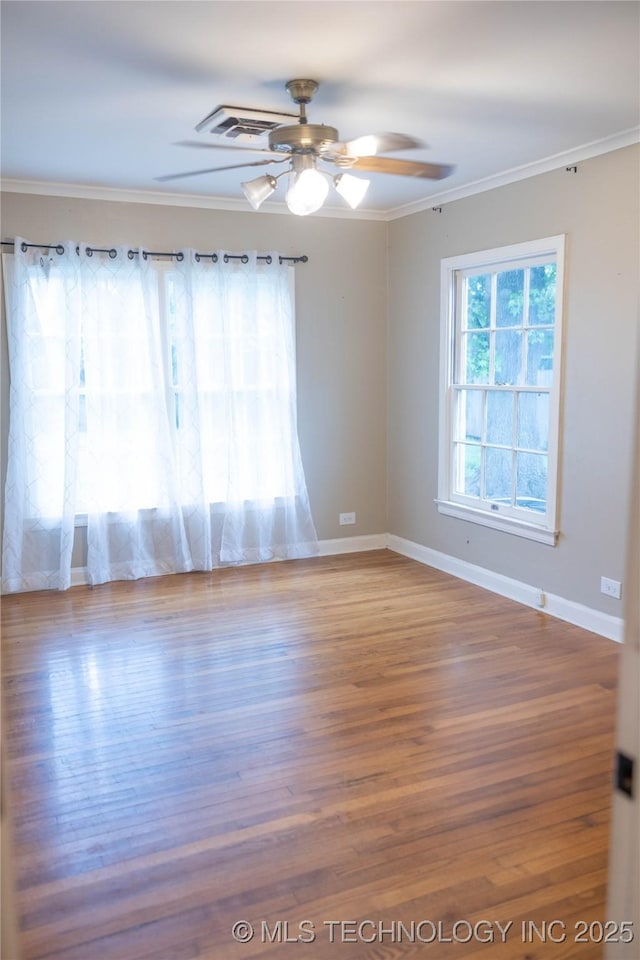 empty room with ceiling fan, baseboards, crown molding, and wood finished floors