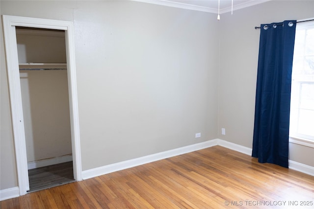 unfurnished bedroom featuring light wood-style flooring, a closet, baseboards, and crown molding