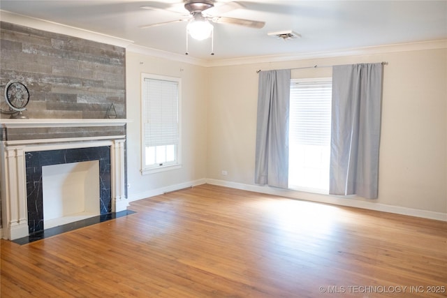 unfurnished living room with ceiling fan, wood finished floors, baseboards, a large fireplace, and ornamental molding