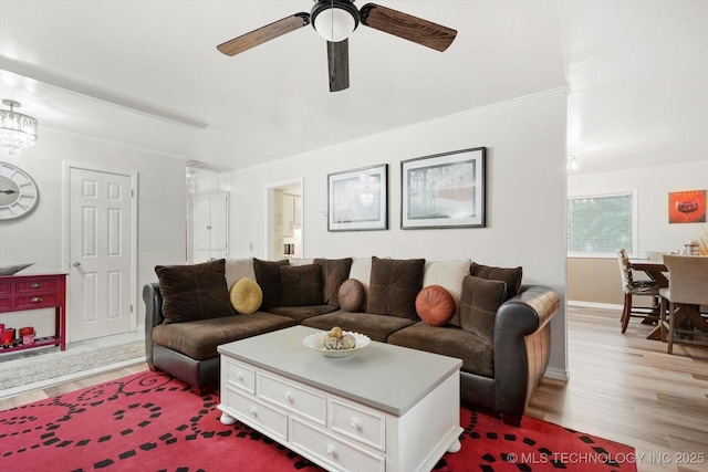 living area featuring wood finished floors, a ceiling fan, baseboards, and crown molding