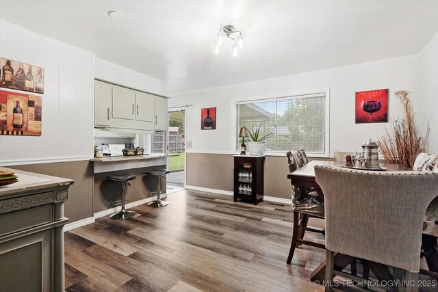 dining area with wood finished floors and ornamental molding