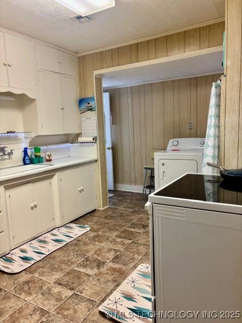 washroom featuring washer / clothes dryer, wooden walls, a sink, and stone finish flooring
