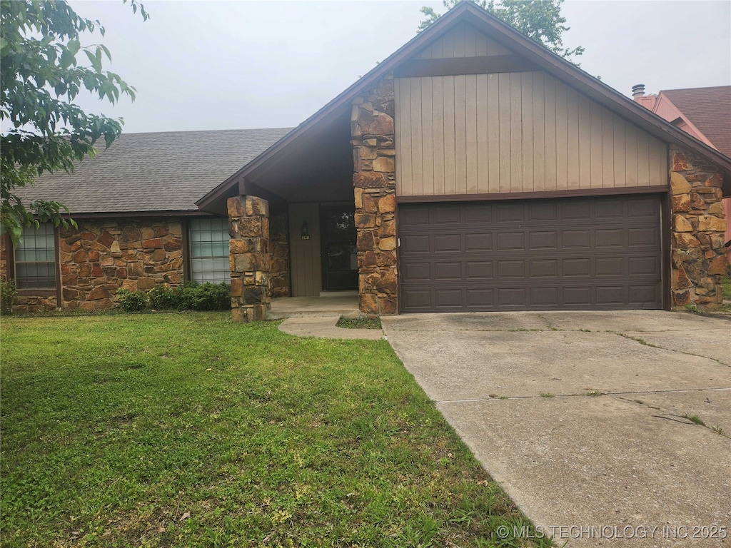 view of front of property with stone siding, an attached garage, driveway, and a front lawn