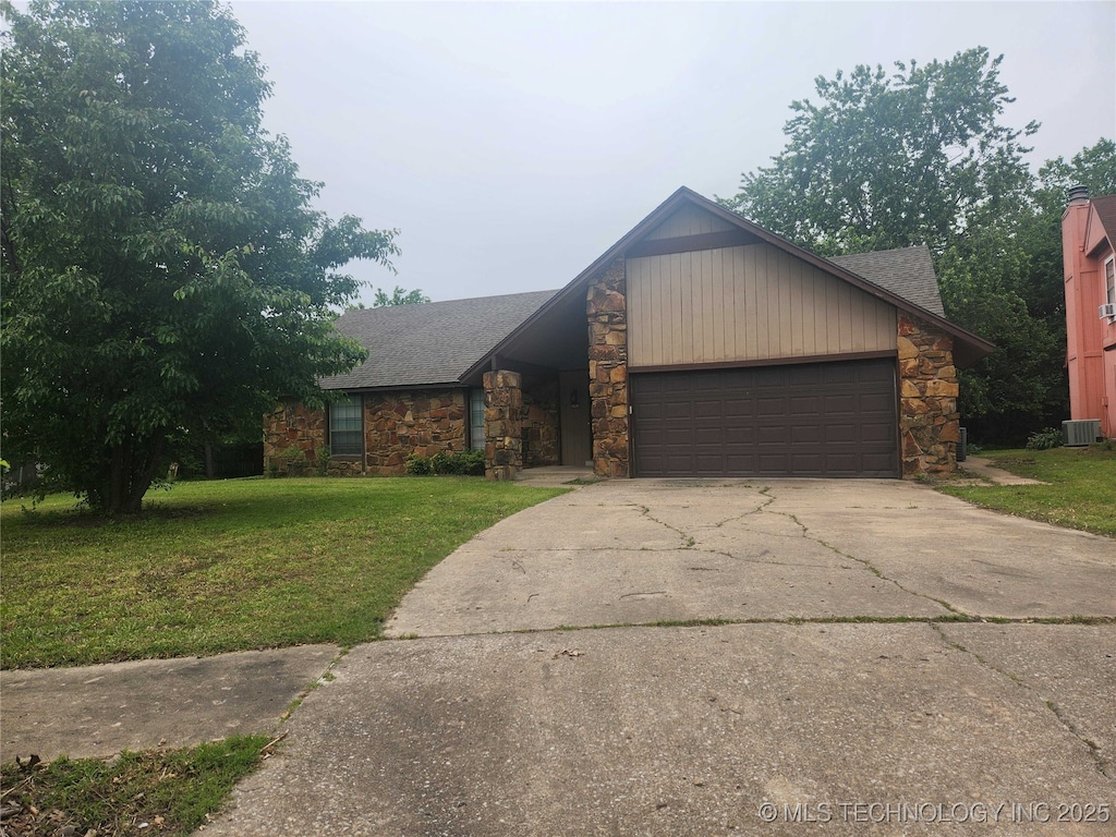 view of front of property with stone siding, a front lawn, cooling unit, concrete driveway, and a garage