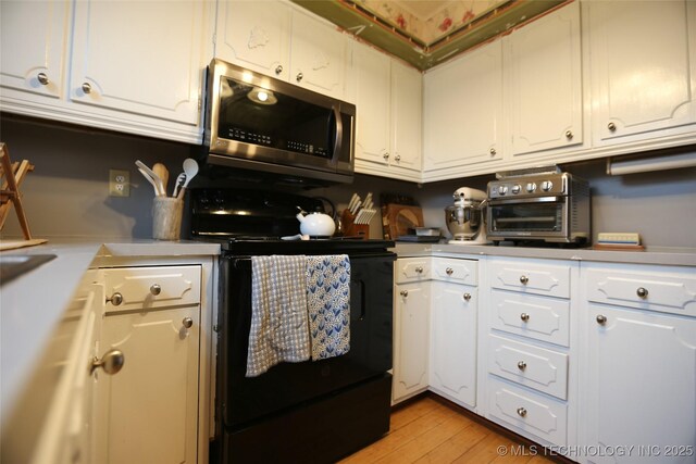 5518 E 46th St Unit 5518, Tulsa, OK 74135 - kitchen featuring stainless steel microwave, black range with electric stovetop, light countertops, white cabinetry, and light wood-style flooring
