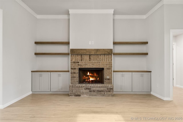unfurnished living room featuring wood finished floors, crown molding, baseboards, and a fireplace