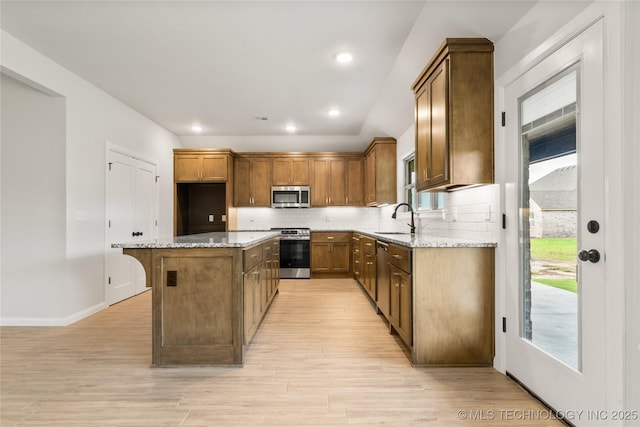kitchen with stainless steel appliances, a sink, light wood-style flooring, a kitchen island, and recessed lighting