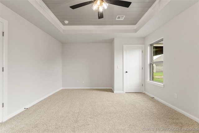 unfurnished bedroom featuring a raised ceiling, carpet floors, baseboards, ceiling fan, and crown molding