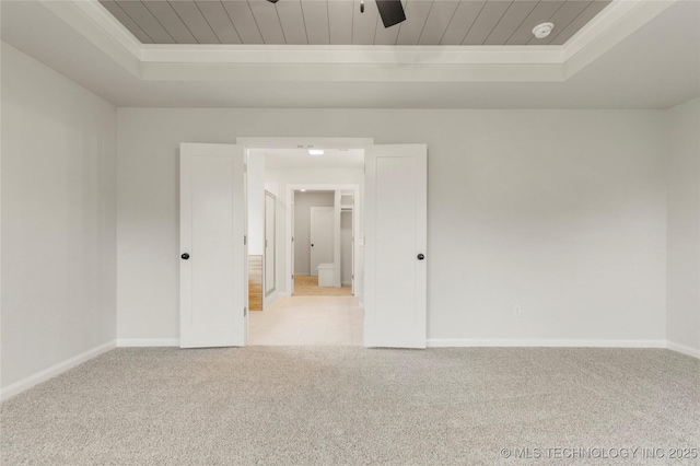 carpeted empty room with a raised ceiling, baseboards, a smoke detector, a ceiling fan, and wood ceiling