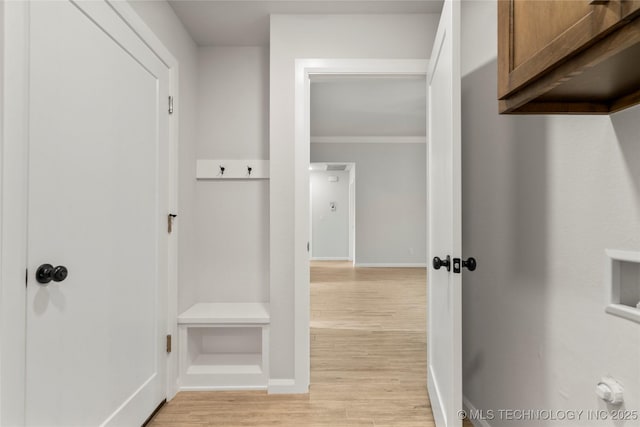 mudroom featuring light wood finished floors, crown molding, and baseboards