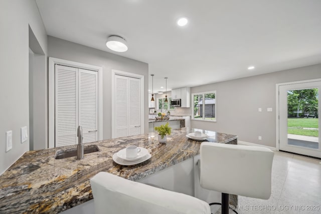 4031 S Birmingham Ave, Tulsa, OK 74105 - kitchen with a sink, stainless steel microwave, a breakfast bar, stone countertops, and recessed lighting