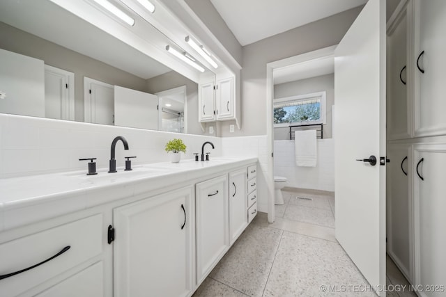 4031 S Birmingham Ave, Tulsa, OK 74105 - full bathroom with tile walls, a wainscoted wall, toilet, and double vanity