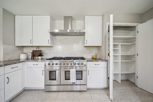 4031 S Birmingham Ave, Tulsa, OK 74105 - kitchen with double oven range, wall chimney exhaust hood, dark stone counters, white cabinets, and dark speckled floor