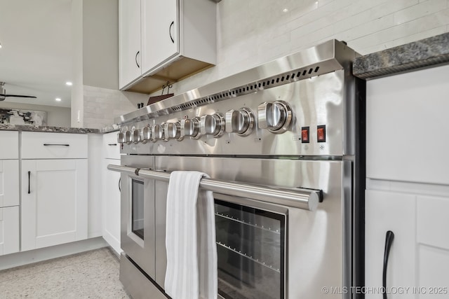 4031 S Birmingham Ave, Tulsa, OK 74105 - kitchen view of stainless steel range, dark stone countertops, white cabinets, dark aggregate flooring, and tasteful backsplash