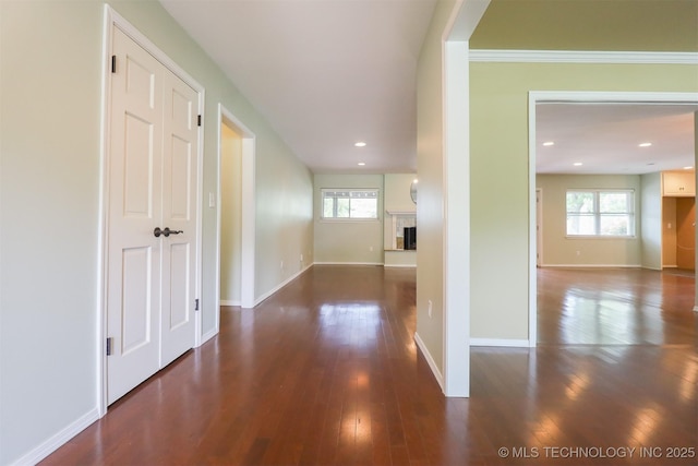 corridor with dark wood-style flooring, baseboards, and recessed lighting