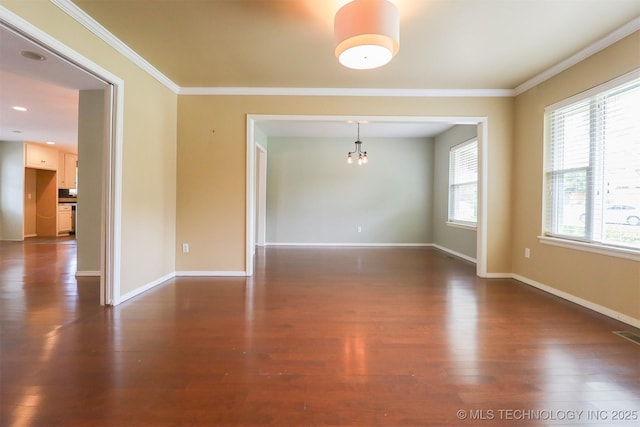 unfurnished room with dark wood-style floors, crown molding, a chandelier, and baseboards