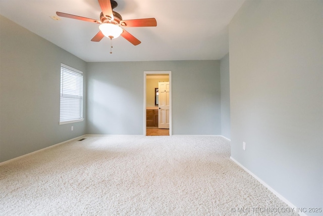 carpeted empty room with a ceiling fan and baseboards