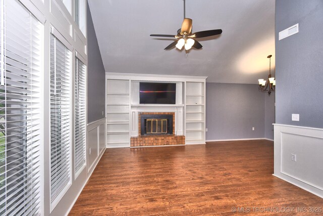 unfurnished living room with a fireplace, ceiling fan, wood finished floors, and a chandelier