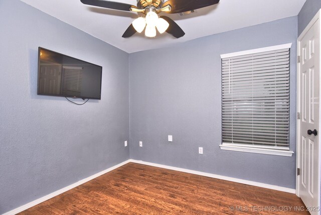empty room featuring dark wood-style floors, ceiling fan, and baseboards