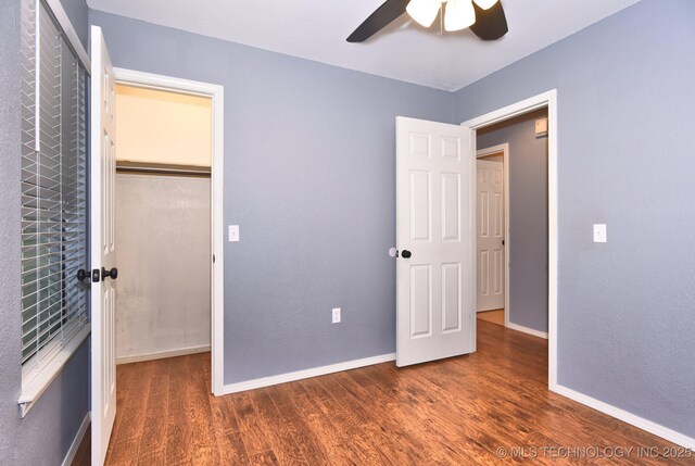 unfurnished bedroom featuring wood finished floors, baseboards, a closet, and ceiling fan