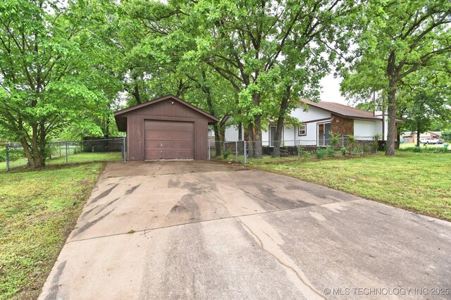 single story home with driveway, a detached garage, and an outbuilding