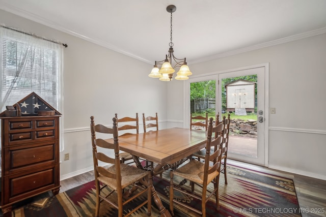 dining space with dark wood-type flooring, a chandelier, crown molding, and baseboards