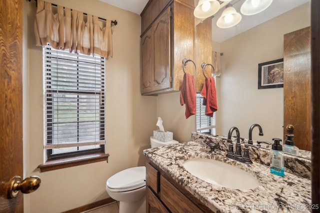 bathroom featuring toilet, vanity, and baseboards