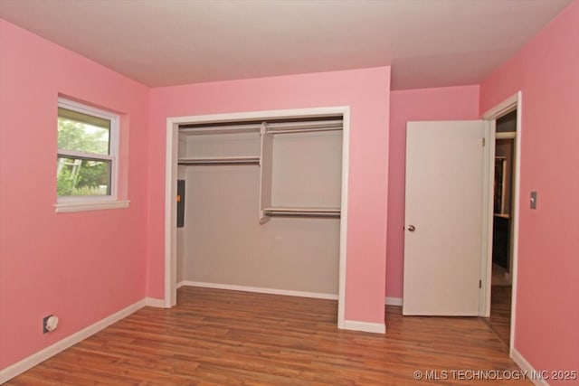 unfurnished bedroom with wood finished floors, baseboards, and a closet