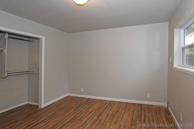 unfurnished bedroom with wood finished floors, a closet, and baseboards