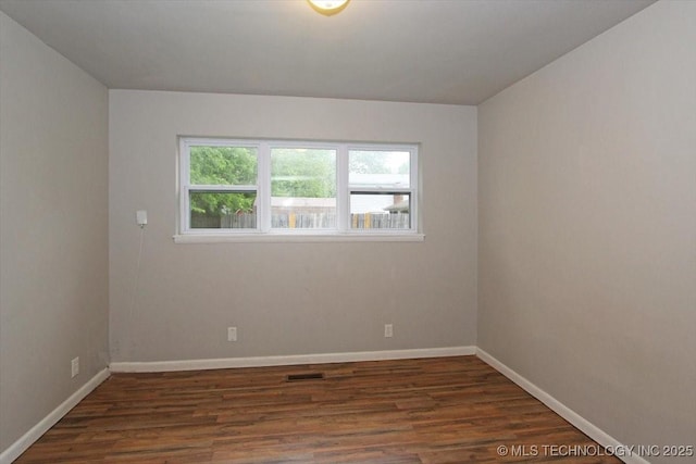 spare room with dark wood finished floors and baseboards