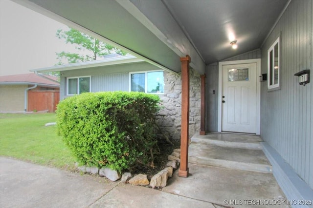 property entrance with stone siding and a yard