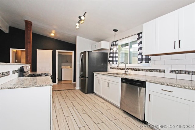 kitchen with appliances with stainless steel finishes, a sink, tasteful backsplash, white cabinetry, and vaulted ceiling