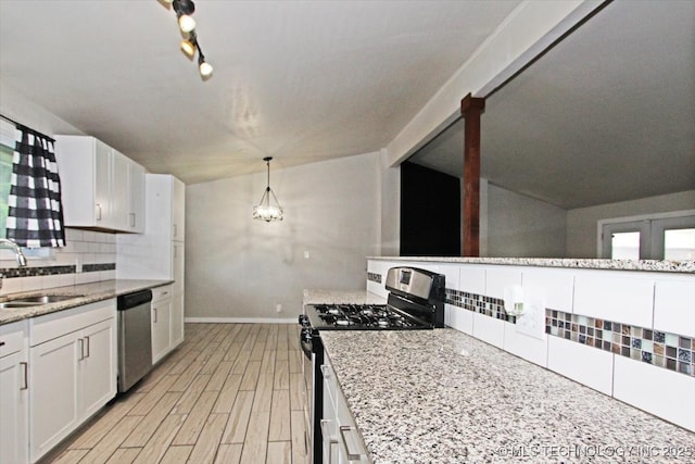 kitchen with appliances with stainless steel finishes, a sink, decorative backsplash, baseboards, and white cabinetry