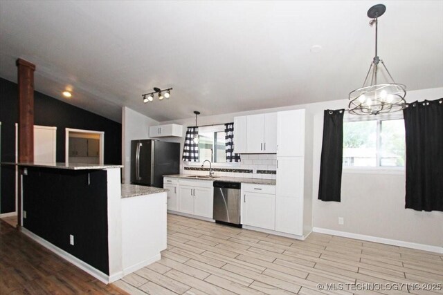 kitchen with freestanding refrigerator, dishwasher, a sink, vaulted ceiling, and white cabinetry