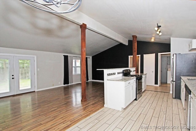 kitchen featuring gas range, light wood-style floors, white cabinets, freestanding refrigerator, and open floor plan