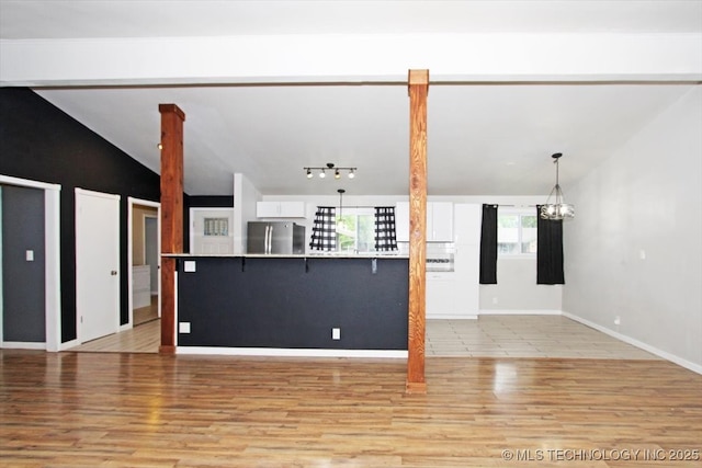 unfurnished living room with vaulted ceiling, light wood-style flooring, and baseboards