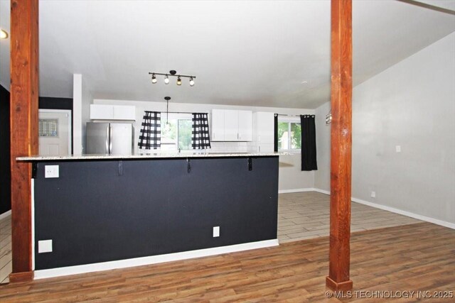 kitchen featuring freestanding refrigerator, white cabinets, light countertops, a breakfast bar, and lofted ceiling