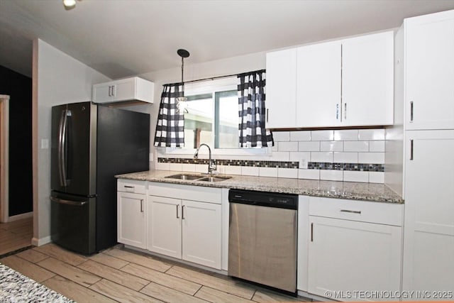 kitchen with a sink, dishwasher, freestanding refrigerator, decorative backsplash, and white cabinetry