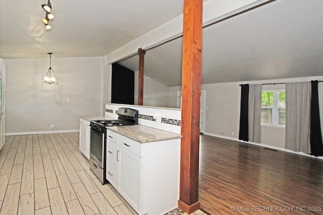 kitchen featuring stainless steel gas range oven, vaulted ceiling, light wood-style flooring, baseboards, and white cabinets