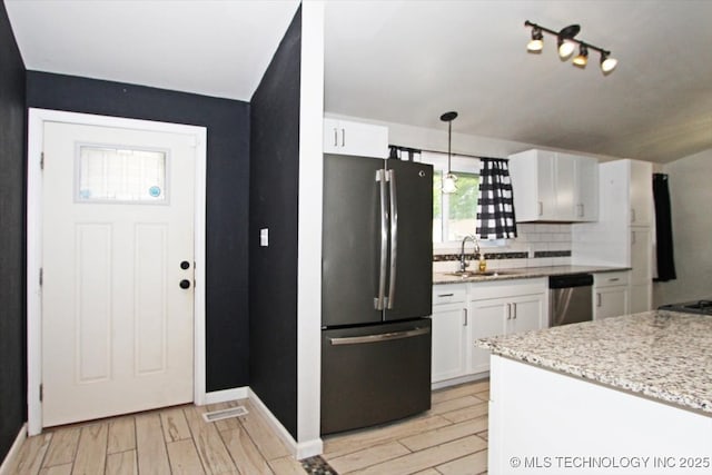kitchen with freestanding refrigerator, a sink, white cabinets, decorative backsplash, and light wood finished floors