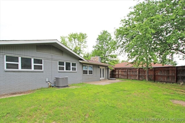 rear view of house featuring a chimney, central AC, brick siding, and a patio