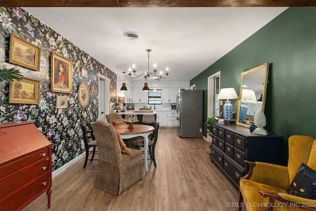 dining space featuring wallpapered walls, light wood-type flooring, a chandelier, and baseboards
