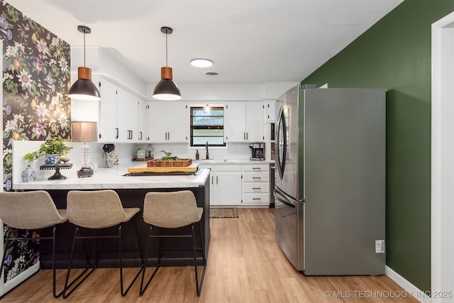 kitchen featuring appliances with stainless steel finishes, a peninsula, white cabinetry, and light wood-type flooring