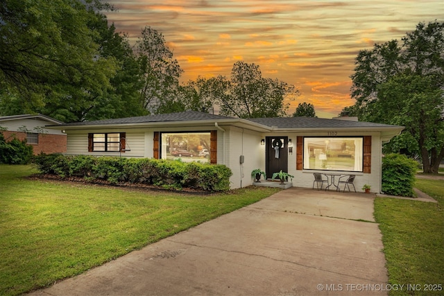 view of front of house with driveway, brick siding, and a front lawn