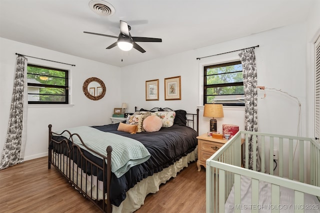 bedroom with light wood-style floors, a ceiling fan, and baseboards