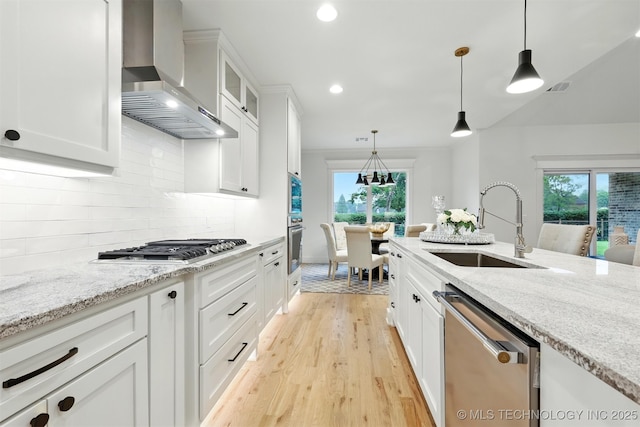 kitchen featuring appliances with stainless steel finishes, wall chimney range hood, a sink, plenty of natural light, and recessed lighting