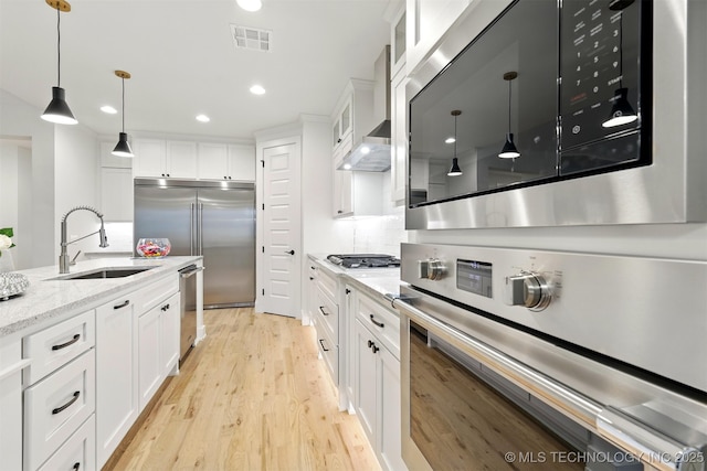 kitchen featuring a sink, appliances with stainless steel finishes, light wood-style floors, glass insert cabinets, and white cabinetry